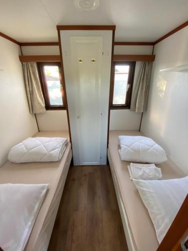 two beds in a small room with two windows at Stacaravanverhuur KR00N chalet BB-5 in Workum