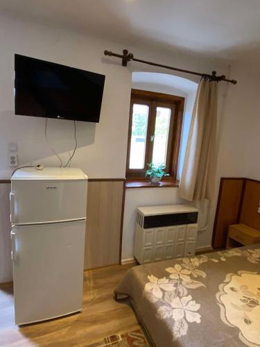 a room with a refrigerator and a television on the wall at Eszter Vendégház Harta in Harta