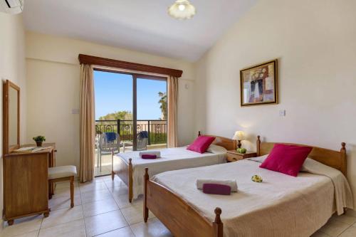 a bedroom with two beds and a balcony at Villa Heracles by Villa Plus in Peyia