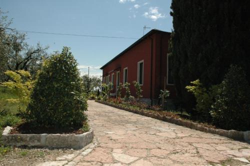 a brick road next to a red building with a tree at Agriturismo Tenuta la Pergola in Bardolino