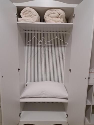 - un placard blanc avec des serviettes sur une étagère dans l'établissement La casa di Titty, à Reggio de Calabre