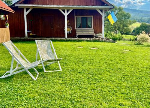 two chairs sitting in the grass in front of a house at Омріяні Карпати in Smozhe