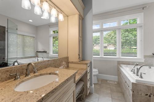 a bathroom with two sinks and a large mirror at Making Waves by AvantStay Sleeps 20 Pool in Westport