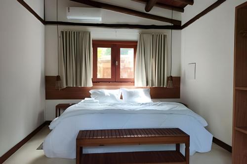 a bedroom with a large white bed and a window at Vida Cajuína Maraú in Marau