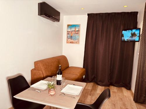 a room with a table with a bottle of wine on it at Appart'hôtel - Seclin-Appartements in Seclin