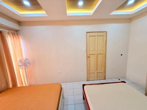 a room with two beds and a door and a fan at 2BR Across Burnham Park Baguio Transient - Unit G in Baguio