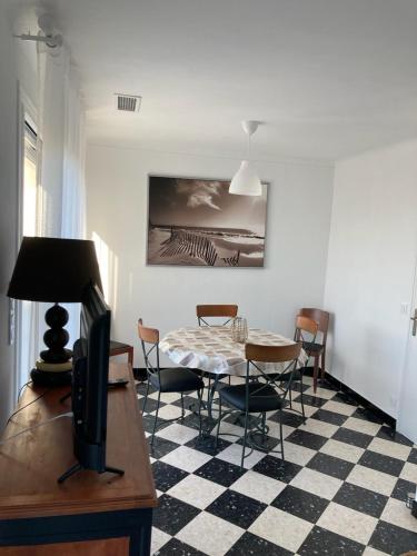 - un salon avec une table, des chaises et une télévision dans l'établissement Grande Villa divisée en deux logements, au Grau-dʼAgde
