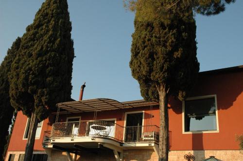 une maison orange avec un balcon et deux arbres dans l'établissement Agriturismo Tenuta la Pergola, à Bardolino