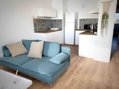 un salon avec un canapé bleu et une cuisine dans l'établissement Appartement face à la mer, à Neufchâtel-Hardelot
