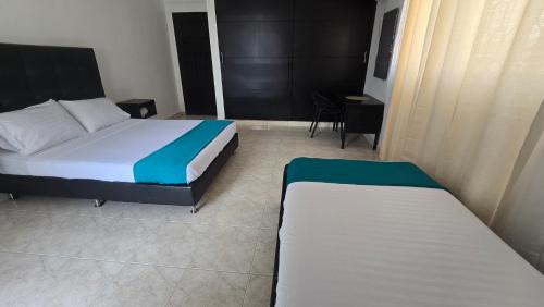 a bedroom with two beds and a table and chairs at Hotel Costa Caribe Barranquilla in Barranquilla