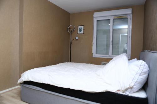 une chambre avec un lit avec des draps blancs et une fenêtre dans l'établissement Appartement T2 Confortable à Lyon, à Lyon