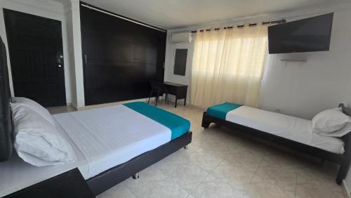a hotel room with two beds and a desk at Hotel Costa Caribe Barranquilla in Barranquilla