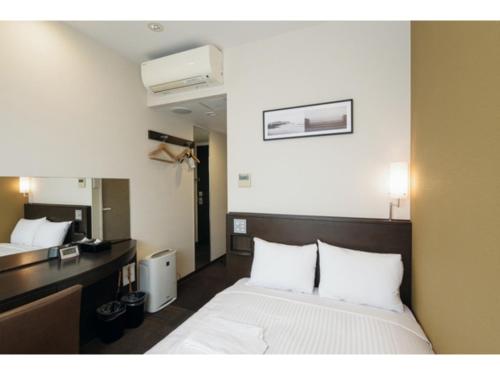 a bedroom with a bed with white sheets and a desk at Kipp Hotel Shonan Fujisawa - Vacation STAY 05487v in Fujisawa