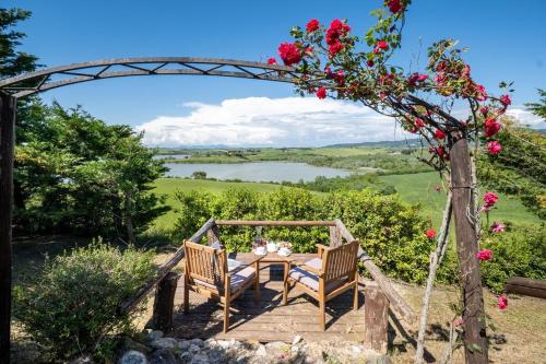 a table with two chairs under an arch with roses at Villa La Lespa W-Pool Biliardo and Lake View in Casa SantʼAndrea