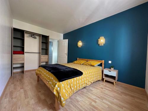 une chambre avec un lit et un mur bleu dans l'établissement Au bout de l'impasse, à Saint-Sulpice-de-Royan