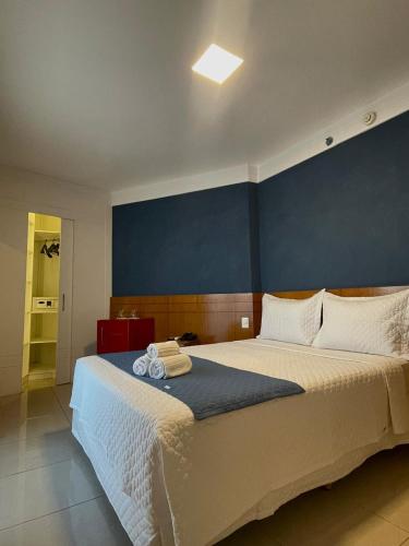 a bedroom with a large bed with a blue wall at Royal Urban Macaé Hotel in Macaé