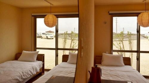 two beds in a room with a view of a parking lot at MUMBU STAY Nantahama Beach - Vacation STAY 13502v in Sonai