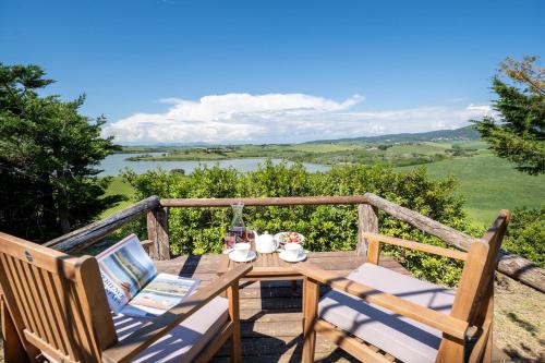 a wooden table and chairs on a deck with a view at Villa La Lespa W-Pool Biliardo and Lake View in Casa SantʼAndrea