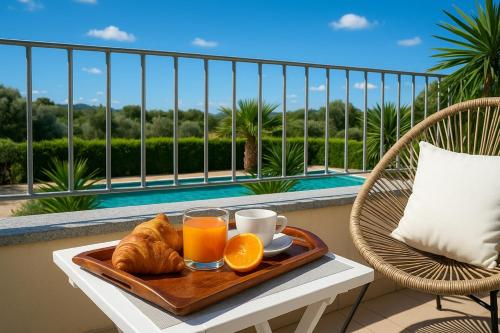 a tray of orange juice and croissants on a table on a balcony at Green Villetta with a pool in Viddalba