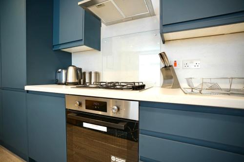 a kitchen with blue cabinets and a stove top oven at Trinity Apartments - 2 Bed Apartment - Spacious - Modern - 30 Seconds from High Street in Huntingdon