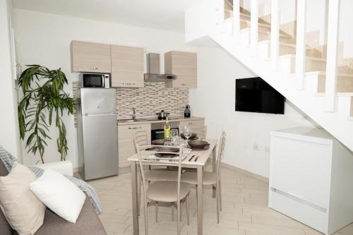 a kitchen and dining room with a table and chairs at Green Villetta with a pool in Viddalba