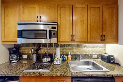 a kitchen with a sink and a microwave at Ski-In Ski-Out Modern Mountain Condo in Winter Park