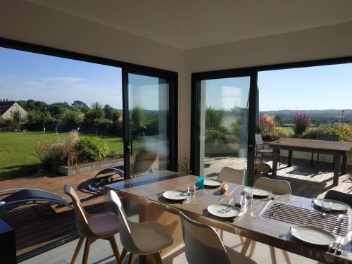 - une salle à manger avec une table, des chaises et de grandes fenêtres dans l'établissement Belle maison entre mer et campagne, à Plouzané
