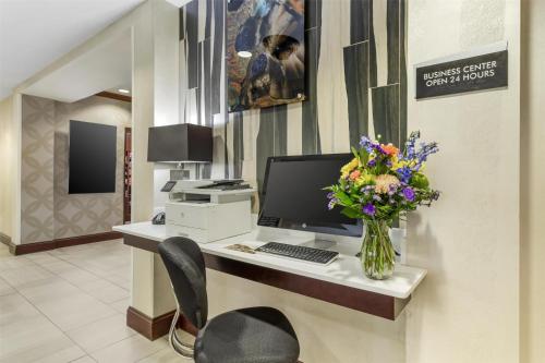 a desk with a computer and a vase of flowers at Best Western Plus River Escape Sylva / Dillsboro in Dillsboro