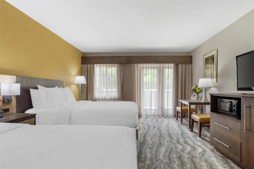 a hotel room with two beds and a flat screen tv at Best Western Plus River Escape Sylva / Dillsboro in Dillsboro