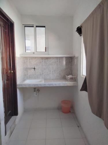 a white bathroom with a sink and a window at Casa Azul in Valladolid