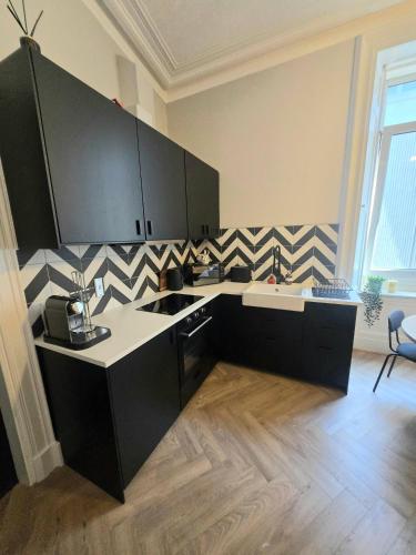 a kitchen with black cabinets and a white counter top at Luxury central apartment w/ 3 beds + 24hr check-in in Aberdeen