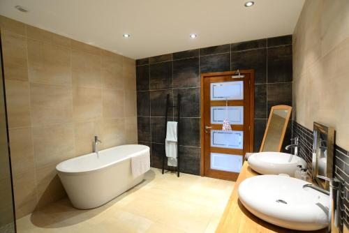 La salle de bains est pourvue d'une baignoire et de 2 lavabos. dans l'établissement Fantastic Holiday Home 5 ensuite bedrooms Pool No Pets, à Désertines