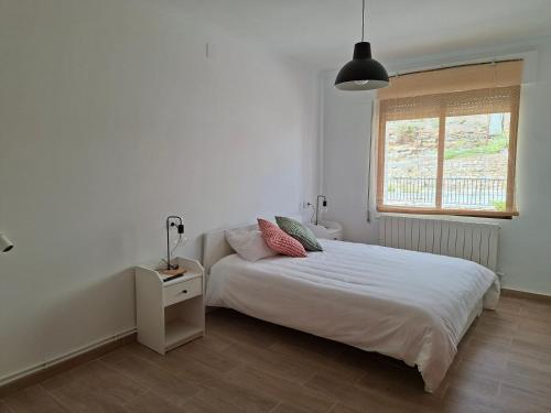 a white bedroom with a bed and a window at Alojamiento Rural El Castillo in Castillo de Villamalefa