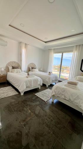 a bedroom with three beds and a large window at Villa Le Domaine Djerba Piscine Chauffée sans vis à vis in Mezraya
