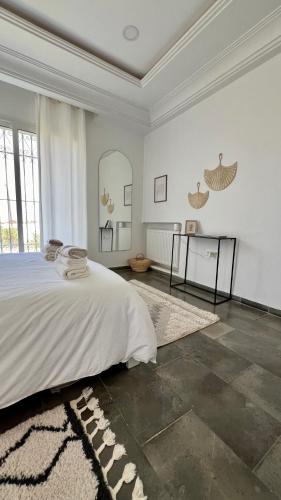 a white bedroom with a bed and a mirror at Villa Le Domaine Djerba Piscine Chauffée sans vis à vis in Mezraya