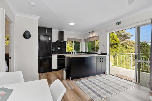 a kitchen with black and white appliances and a balcony at Nana Glads of Paihia in Paihia