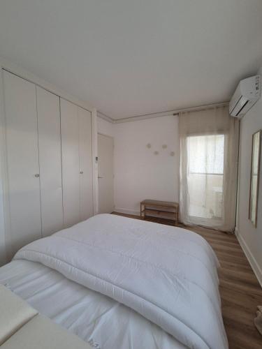 une chambre blanche avec un grand lit et une fenêtre dans l'établissement L'évasion catalane, au Barcarès