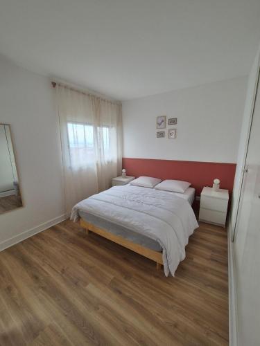 une chambre avec un grand lit et un mur rouge dans l'établissement L'évasion catalane, au Barcarès