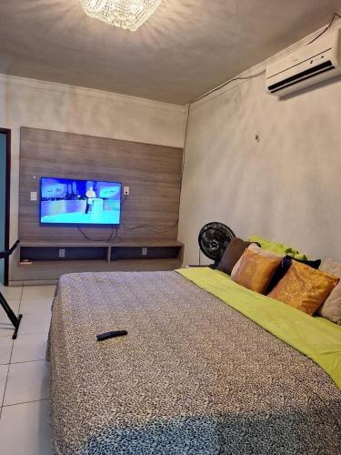 ein Schlafzimmer mit einem großen Bett und einem Flachbildfernseher in der Unterkunft Flat-House Veraneio in Macajatuba