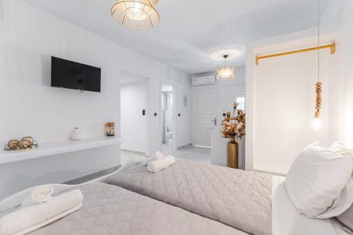 a white bedroom with a large bed and a bathroom at Golden Bay in Agios Prokopios