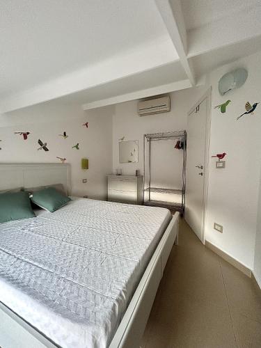 a bedroom with a white bed with birds on the wall at Evergreen Terrace in Giardini Naxos