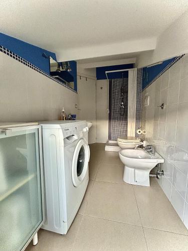 a bathroom with a washing machine and a toilet at Evergreen Terrace in Giardini Naxos