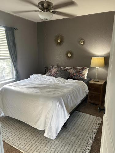 a bedroom with a white bed with a ceiling fan at Quaint & Vivacious Room-Queen in Kyle