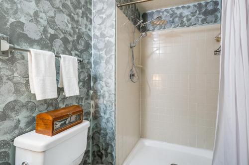 a bathroom with a shower and a toilet with a clock on it at 1 Mi to Boardwalk Convenient North Beach Apt! in North Beach