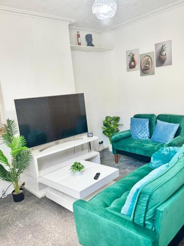 a living room with a green couch and a flat screen tv at Ridley Premium Stay in Leicester