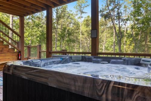 a large hot tub on the deck of a cabin at Cozy Luxe Cabin Hot Tub Firepit in Broken Bow