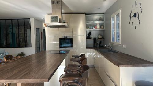 - une cuisine avec un comptoir en bois et des tabourets dans l'établissement Chambre d'hôte dans une maison cosy, à Saint-Martin-de-Crau