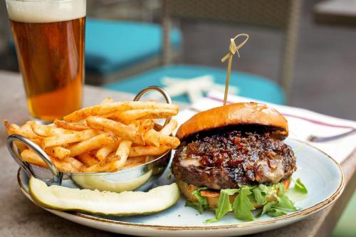 a plate with a hamburger and french fries and a glass of beer at San Diego Marriott La Jolla in San Diego