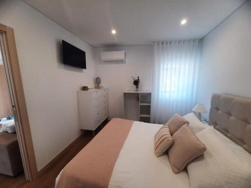 a bedroom with a bed and a dresser and a television at Casas Peralta - Outeiro in Arouca