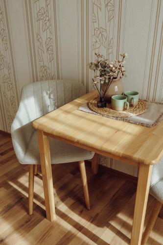 a wooden table with a chair and two cups on it at Telegrāfs Hotel in Ventspils
